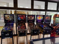 A row of several classic pinball machines lined up inside a brightly lit room.