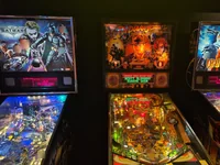 Trois flippers illuminés représentant Batman, Indiana Jones et Iron Man alignés côte à côte. - Photo par Solar_Rider (25 Jul 2026)