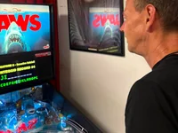 A person plays the Jaws pinball machine with a movie poster on the wall. - Photo by PinballJim (30 Jul 2026)