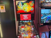 A Pokemon themed pinball machine is displayed in a brightly lit arcade setting.